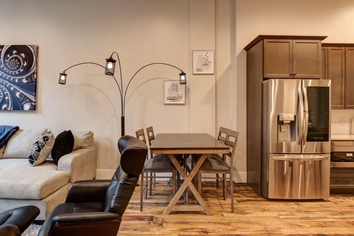 The image presents an inviting, open-concept living and dining area with a cozy sofa and a dining table set for gatherings. The space is ideal for shared meals, game nights, or relaxing together after exploring the city, with modern touches that speak to both comfort and style.