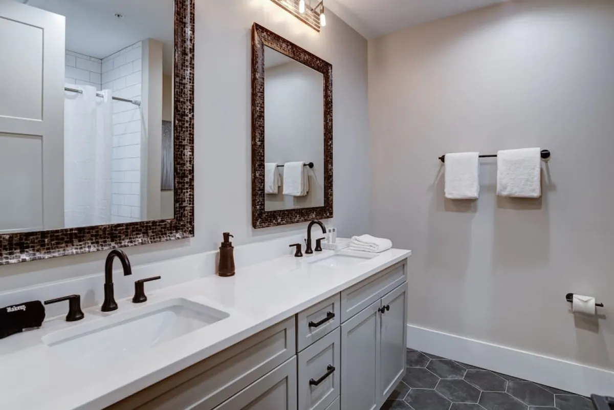 A modern, elegant bathroom with a double vanity, stylish mirrors, and refined lighting fixtures. The space is bright and inviting, ideal for refreshing morning routines or calming evening rituals.