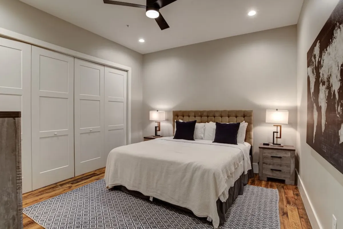 A serene king bedroom featuring a plush bed with crisp linens, elegant nightstands with modern lighting, and a striking world map artwork that adds a touch of personality. The room exudes tranquility and comfort, perfect for relaxation or quiet reading.